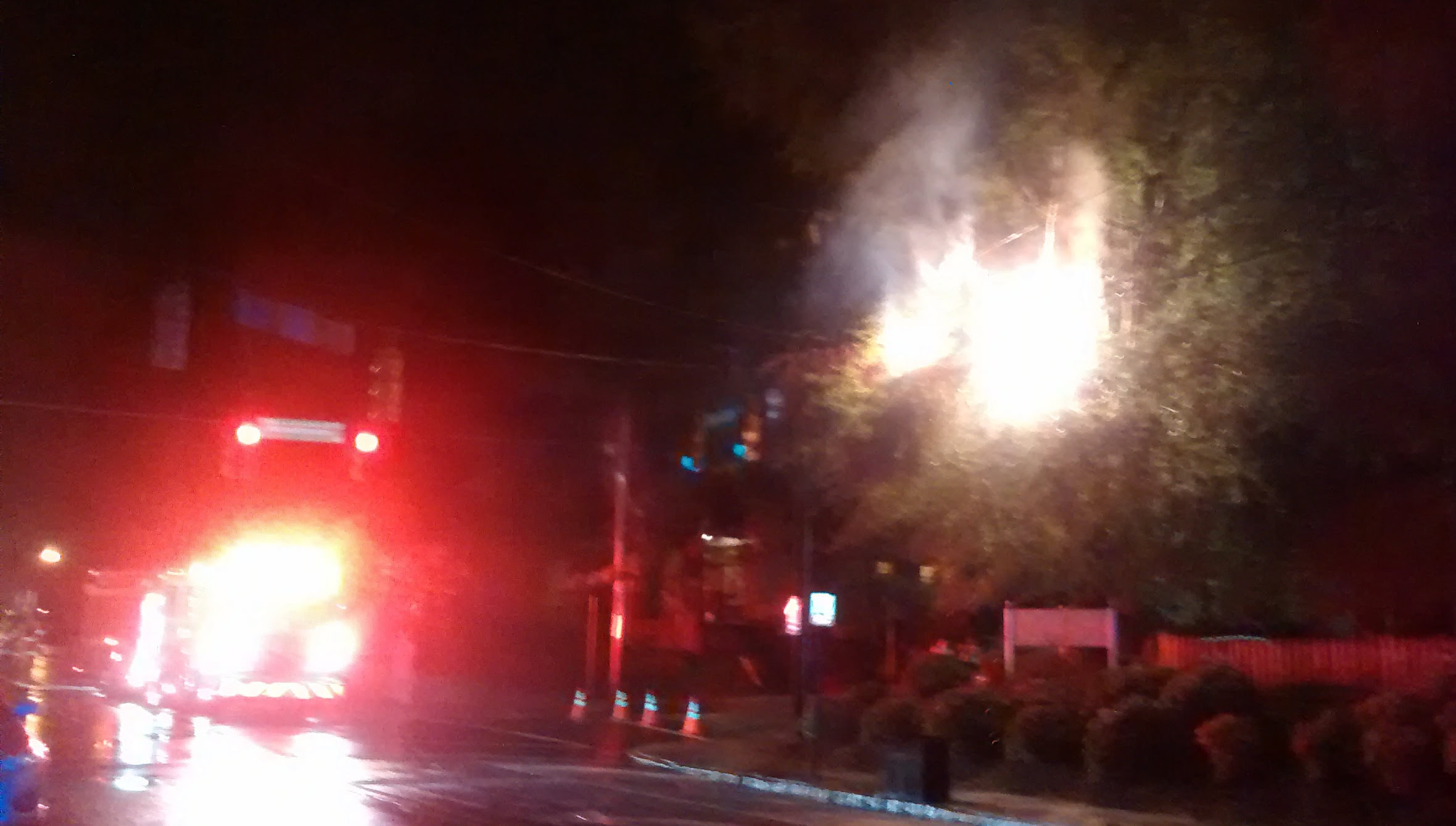 A blown transformer, a burning tree and a fire truck light up the rainy evening on Spring Garden Street.