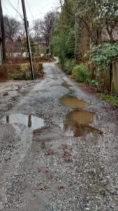 gravel street with potholes filled with rainwater