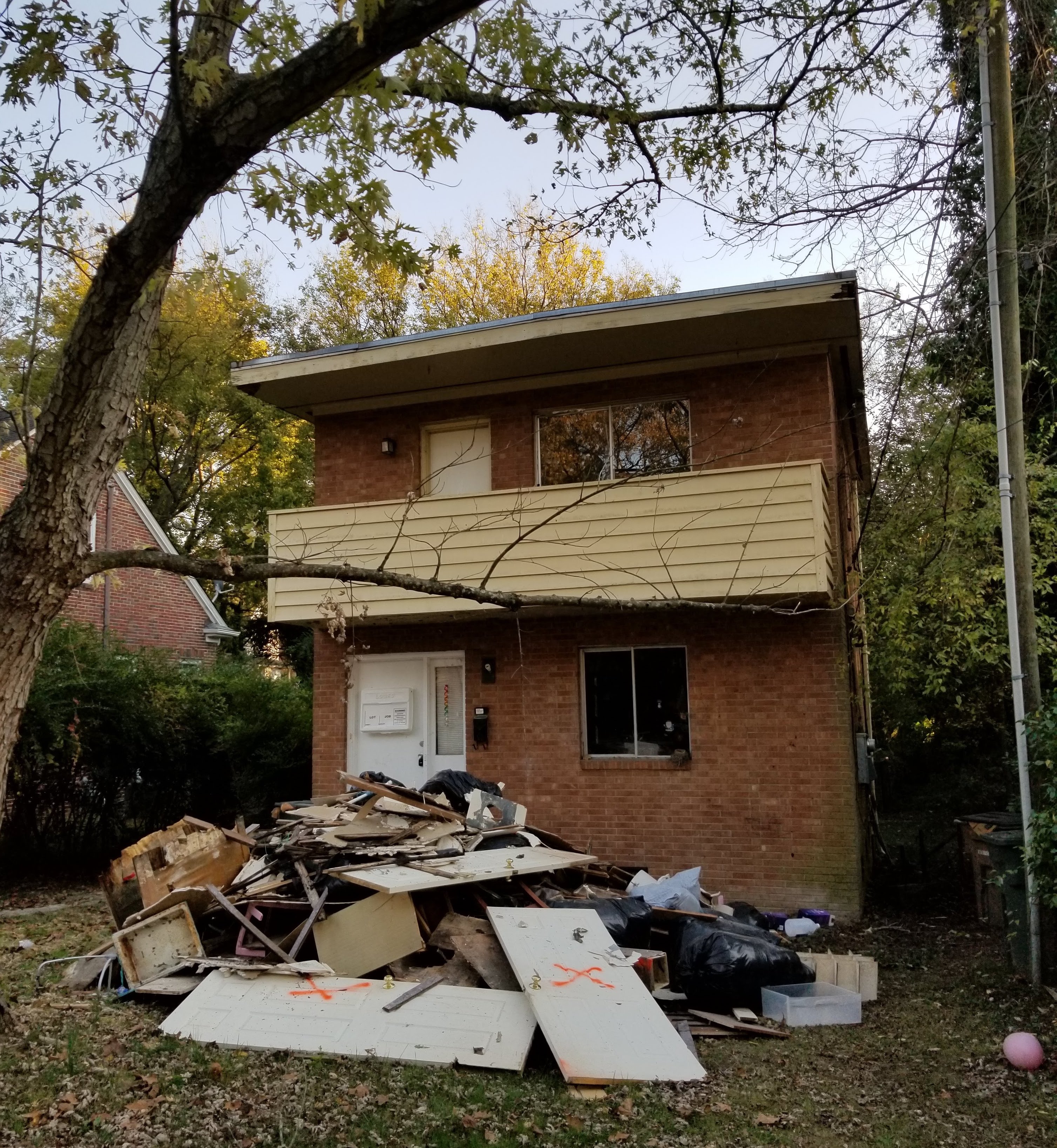 the same house, with a large pile of debris in the front yard